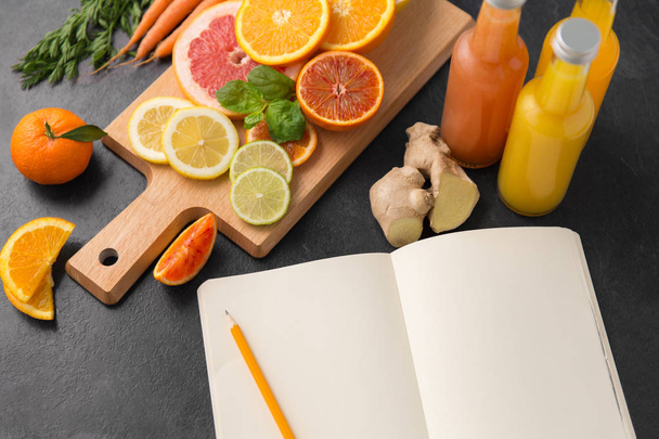 close up of fruits, juices and notebook on table - Fotó, kép