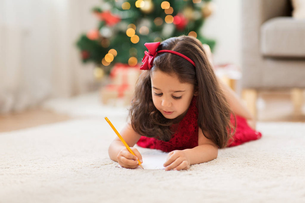 little girl writing christmas wish list at home - Foto, afbeelding