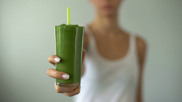 Dopasuj kobieta trzyma zielony koktajl dla weight loss, pożywny napój na śniadanie - Materiał filmowy, wideo