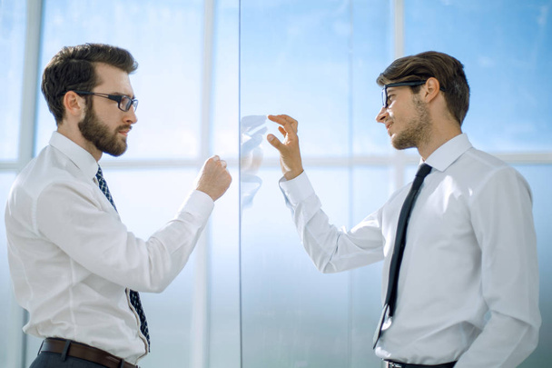 Two businessmen standing in a modern office with glass walls - Zdjęcie, obraz
