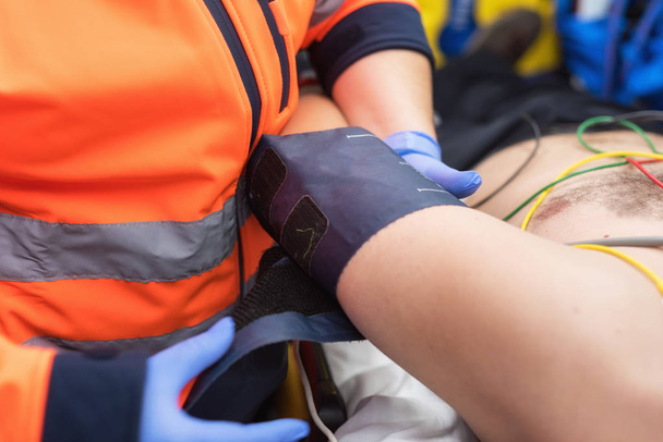 Médico de emergência verificando a pressão arterial de um paciente na ambulância
 - Foto, Imagem