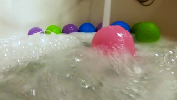 Pink plastic ball rolled by water stream in bath tub, slow motion - Footage, Video