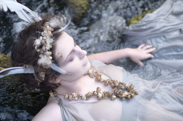 mujer joven en una corona de plumas y conchas
 - Foto, imagen