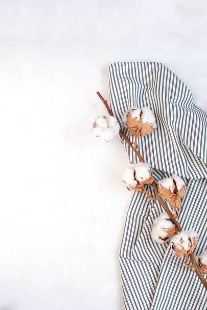 Concepto de decoración de otoño mínimo - Rama de algodón seco sobre servilleta de rayas arrugadas, fondo blanco. Simplicidad y suavidad. Vista superior, espacio de copia
. - Foto, Imagen