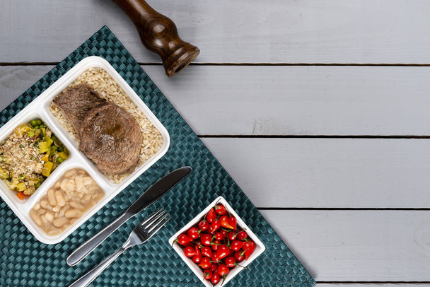 Witte bonen bruine rijst met gebakken vlees en groenten. Braziliaanse lunchbox. Vooruit maaltijd voorbereiding of dieet concept. bovenaanzicht. - Foto, afbeelding