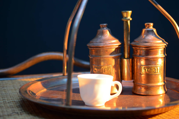 una tazza di caffè vicino alla zuccheriera e un contenitore con caffè su un vassoio di rame e un tavolo di rattan
 - Foto, immagini