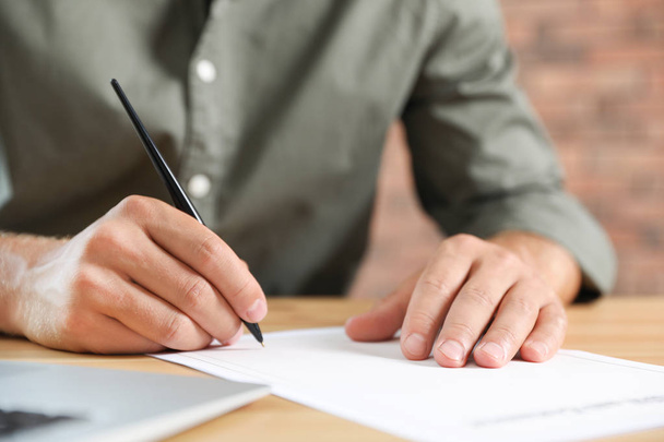 Mannelijke notaris ondertekenen document aan tafel in kantoor, close-up - Foto, afbeelding