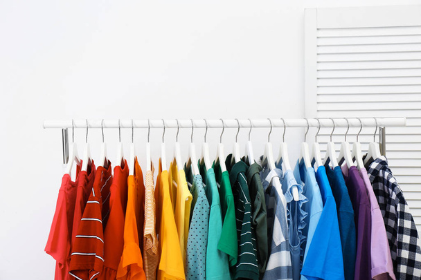 Rack with bright clothes in room. Rainbow colors - Fotoğraf, Görsel