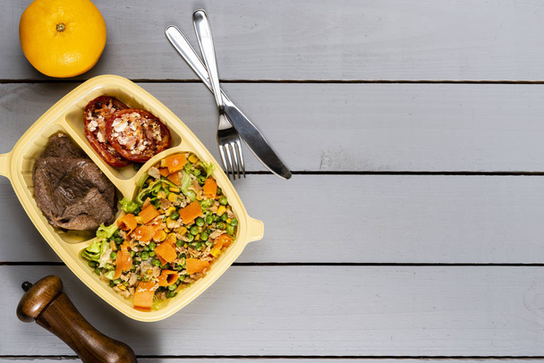 Мясо и помидоры с салатом. Бразильская коробка для обеда. Впереди приготовление пищи или диета концепции. вид сверху
. - Фото, изображение