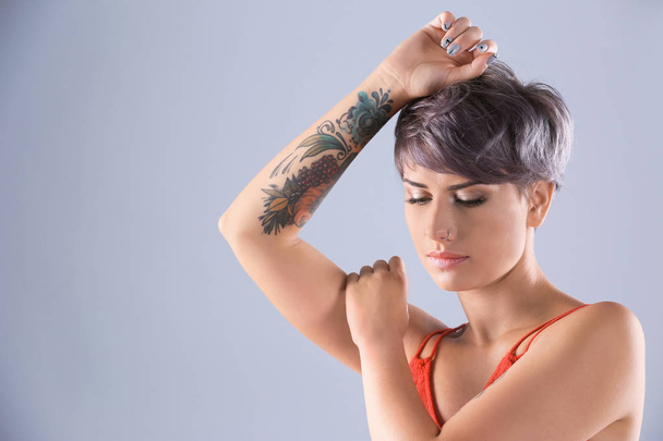 Young woman with tattoos on color background - Foto, Imagen