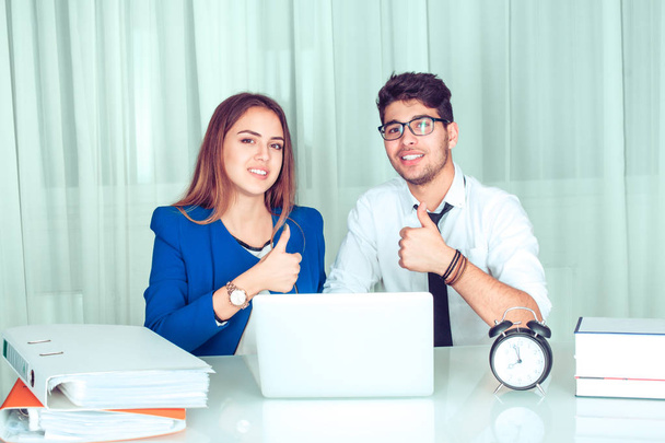 Cheerful modern smart couple colleagues man, woman with laptop at office table showing thumbs up like and smiling at camera sitting at table in living room at home Freelance work happy workers concept - Valokuva, kuva