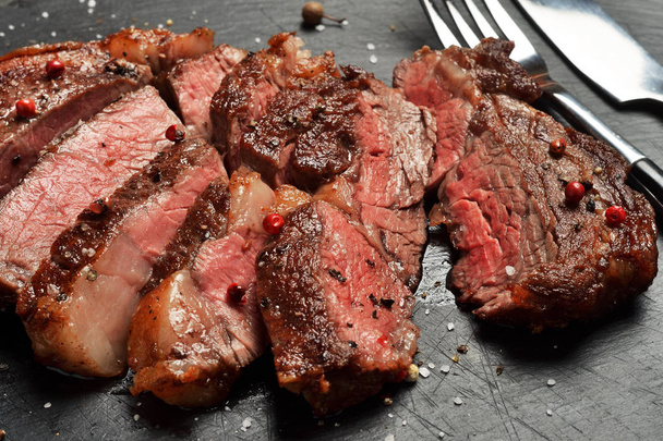 Prime Black Angus Ribeye steak on black stone plate. Medium Rare degree of steak doneness. - Photo, image