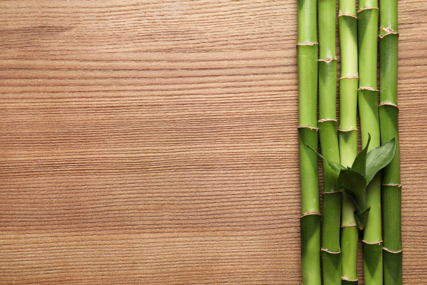 Green bamboo stems and space for text on wooden background, top view - Fotoğraf, Görsel