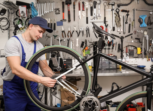 Professional mechanic repairing bicycle in modern workshop - Foto, Bild