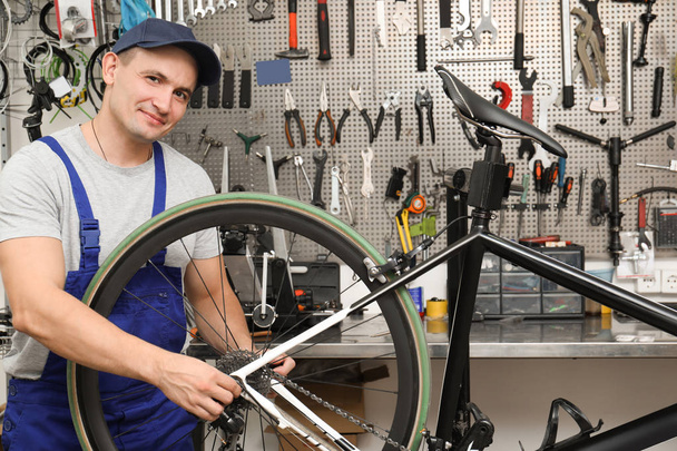 Professional mechanic repairing bicycle in modern workshop - Fotó, kép