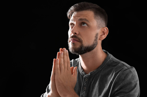 Man with hands clasped together for prayer on black background. Space for text - Фото, зображення