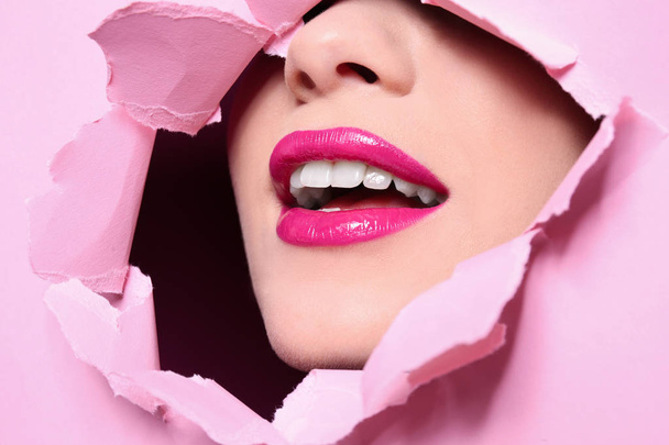 View of beautiful young woman with perfect lips makeup through hole in color paper - Фото, зображення
