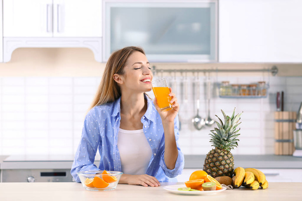 Woman with glass of orange juice at table in kitchen. Healthy diet - Foto, Bild