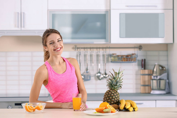 Woman with glass of orange juice on table in kitchen. Healthy diet - Zdjęcie, obraz
