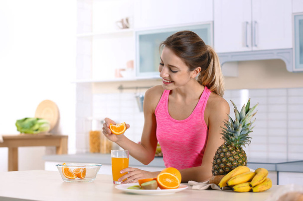 Woman making orange juice at table in kitchen. Healthy diet - Fotoğraf, Görsel