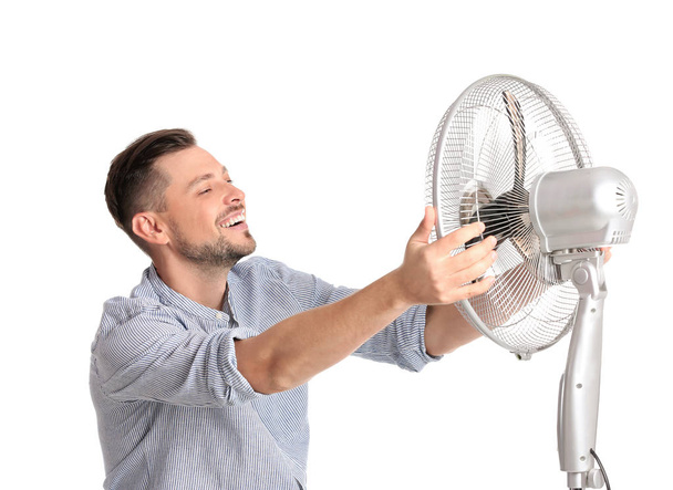 Man refreshing from heat in front of fan on white background - Foto, afbeelding