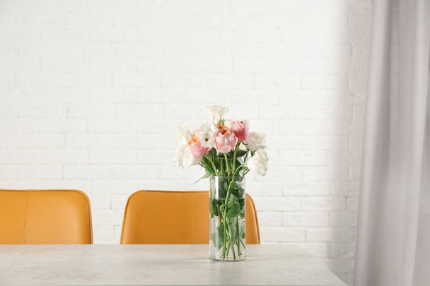 Βάζο με όμορφα λουλούδια ως στοιχείο του εσωτερικού σχεδίου στο τραπέζι στην αίθουσα - Φωτογραφία, εικόνα