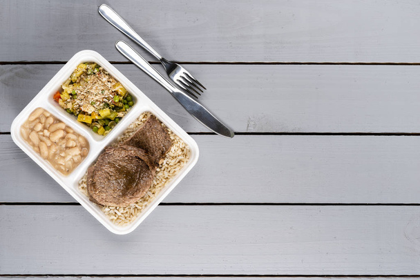 Белая фасоль коричневый рис с колбасой и овощами. Бразильская коробка для обеда. Впереди приготовление пищи или диета концепции. вид сверху
. - Фото, изображение