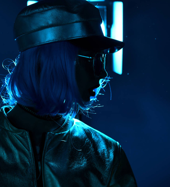 woman in street style fashion winter concept wearing gold hat cap and round sunglasses in pink neon light - Foto, Imagem