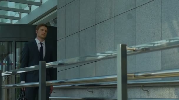 Handsome businessman leaving office building, productive working day, success - Felvétel, videó