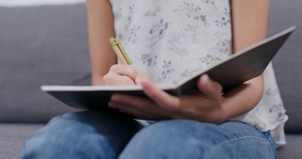 Frau schreibt zu Hause am Notizbuch - Foto, Bild