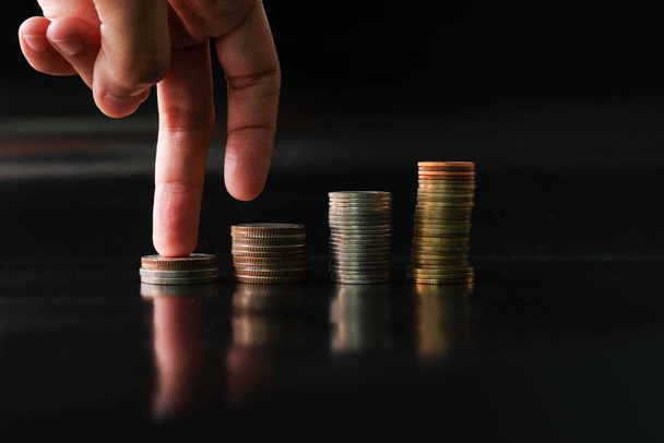 fingers step upward on stack of coins on black background concept business finance growing - Foto, Imagem