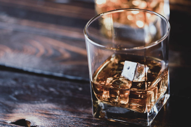 Alcohol drinken whisky, whiskey of bourbon met ijsblokjes op donkere houten tafel - Foto, afbeelding