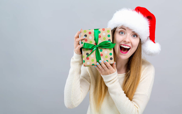 Young woman with santa hat holding a gift box - Foto, Imagen