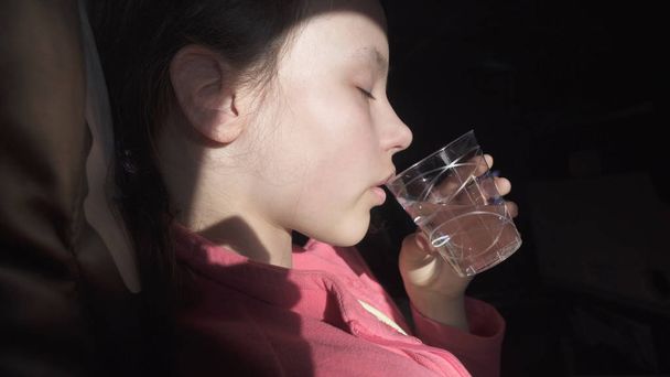 Sad teenage girl drinks water from an ailment in the cabin of plane while traveling - Fotó, kép