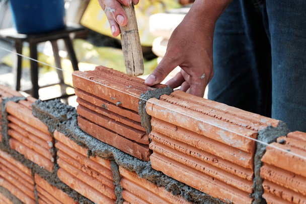 Bricklayer werknemer installeren baksteen metselwerk op buitenmuur. - Foto, afbeelding