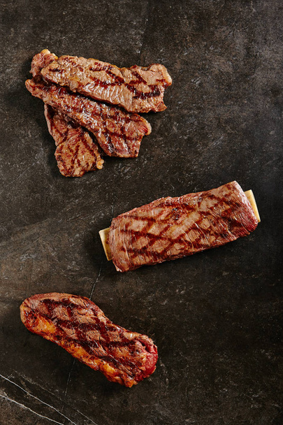 Hot Fresh Gaucho Steak and Flank Steak on Barbecue Grill Background. Ready to Eat Tri-tip Grillsteak with Beef and Well Done Bbq Entrecotes. Thick Slices of Fried Meat with Bone Top View - Valokuva, kuva