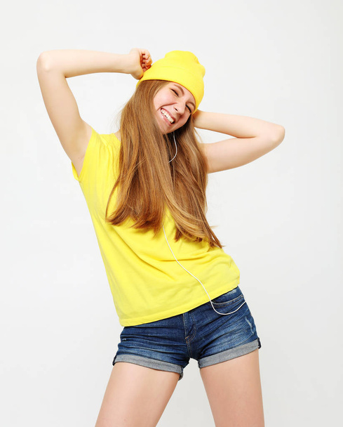Girl in yellow t-shirt dancing with inspired face expression. Active young woman in casual summer outfit having fun indoor - 写真・画像