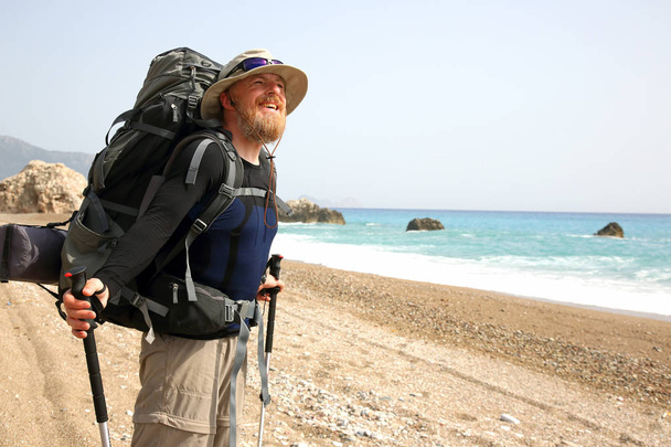 viajero barbudo con mochila en el paseo marítimo disfruta de la luz del sol
 - Foto, imagen