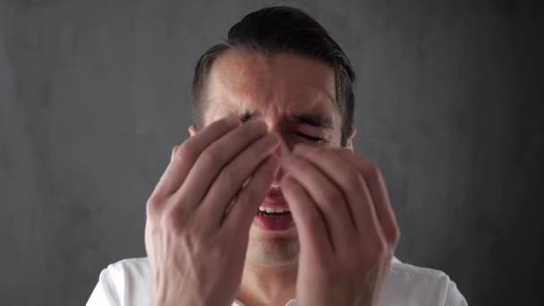 Epätoivoissaan oleva nuori mies itkee peittäessään kasvonsa kädellään. Liikemies itkee kyynelistä. Liiketoiminnan romahtaminen
. - Materiaali, video