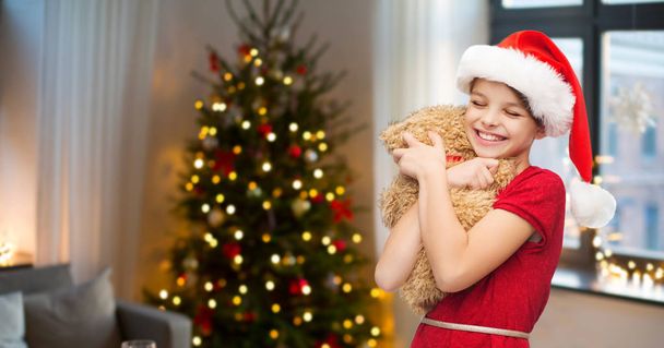 girl in santa hat with teddy bear on christmas - Photo, Image