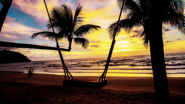 Palmu ja keinu rannalla auringonlaskun kanssa
. - Valokuva, kuva