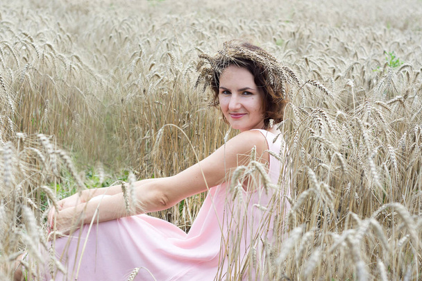 A természet élvezete. Nő búza mező elölnézet ül - Fotó, kép