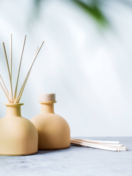 aroma reed fragrance diffusers with rattan sticks with palm leaf on light grey background - Foto, Bild