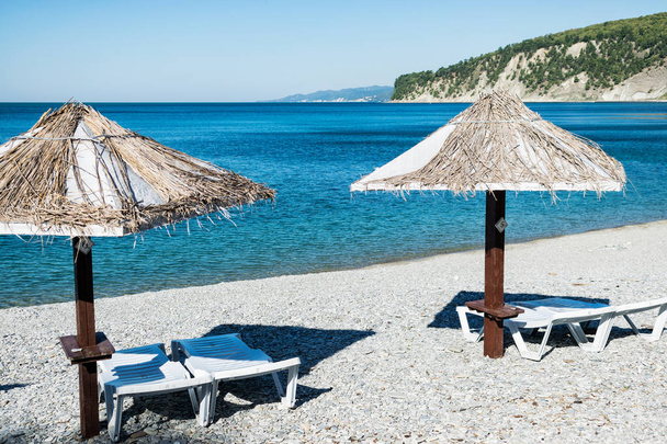 Beach umbrellas and sun beds on the ocean. Vacation and travel to different countries - Photo, image