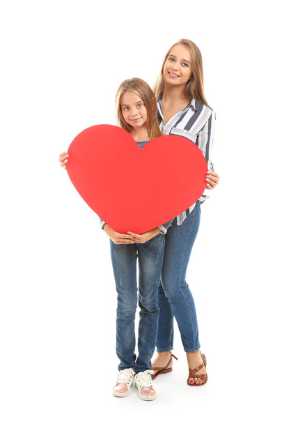 Το χαριτωμένο μικρό κορίτσι και η μητέρα της με μεγάλη καρδιά κόκκινο σε λευκό φόντο - Φωτογραφία, εικόνα