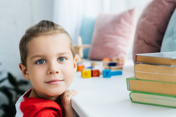child standing at surface with books and colorful blocks at home - Photo, Image