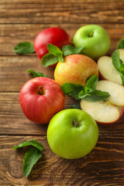 Knippen en hele verse rijpe appels met munt op houten tafel - Foto, afbeelding
