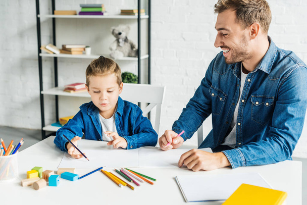 happy young father drawing with adorable little son at home - Photo, Image