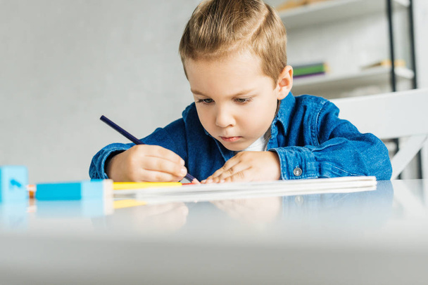 συμπυκνωμένο μικρό παιδί, σχέδιο με μολύβια χρώματος στο σπίτι - Φωτογραφία, εικόνα