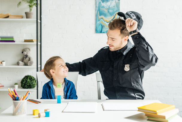 smiling young father in police uniform and son spending time together at home - 写真・画像